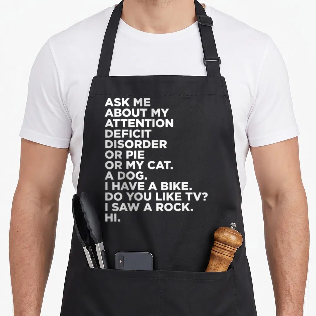 Ask adhd apron - White stacked text reading Ask Me About My Attention Deficit Disorder Or Pie Or My Cat A Dog I Have — shown on a black cotton canvas apron against a white background