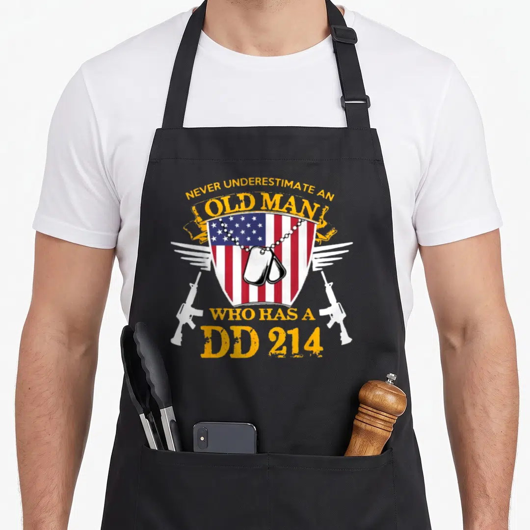 Underestimate air force mom apron - Distressed shield with DD 214 text, dog tags, wings, and crossed rifles in red — shown on a black cotton canvas apron against a white background