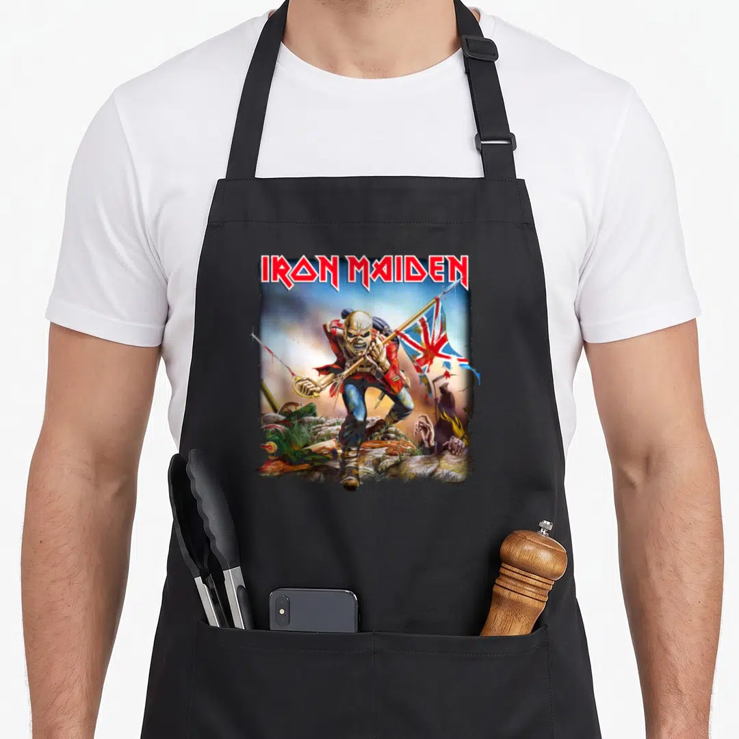 Trooper camping apron - IRON MAIDEN text above skeleton soldier holding rifle and flag among rocks — shown on a black cotton canvas apron against a white background