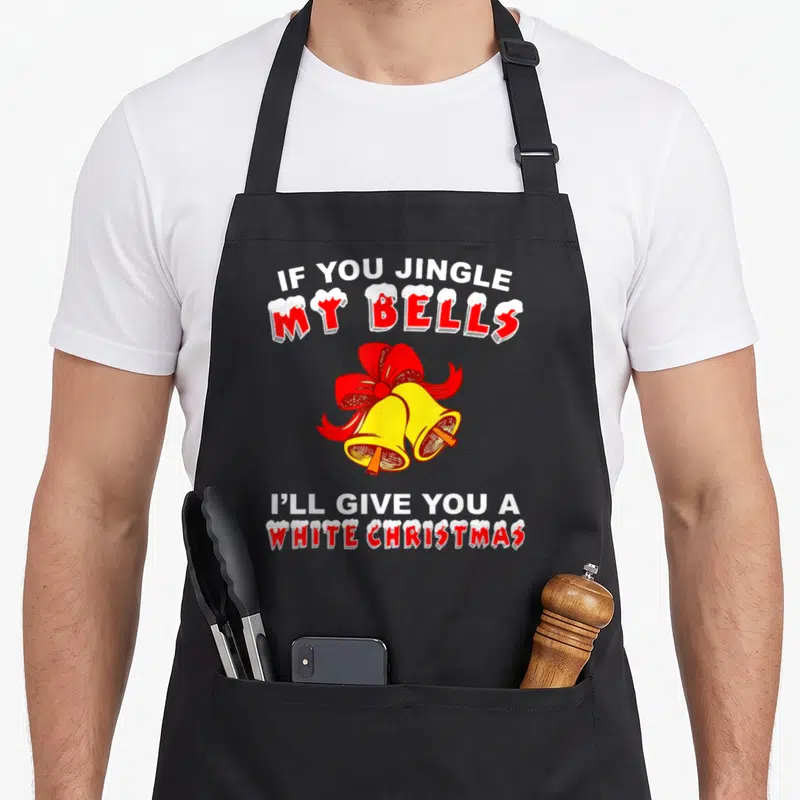 Jingle christmas apron - Two yellow bells with red bow and IF YOU JINGLE MY BELLS pun text — shown on a black cotton canvas apron against a white background