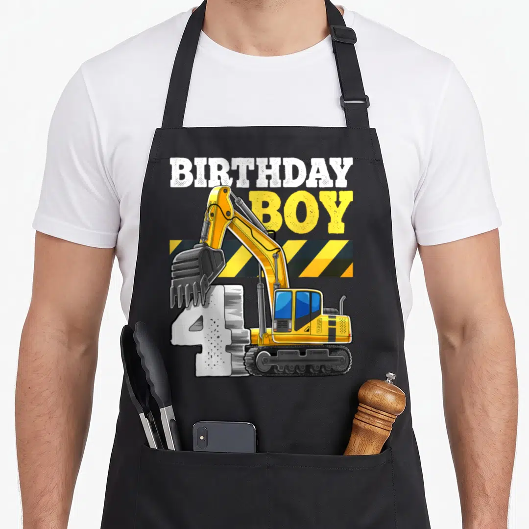 4th vehicle apron - Yellow excavator bucket on white number 4 under BIRTHDAY BOY text with hazard stripes — shown on a black cotton canvas apron against a white background