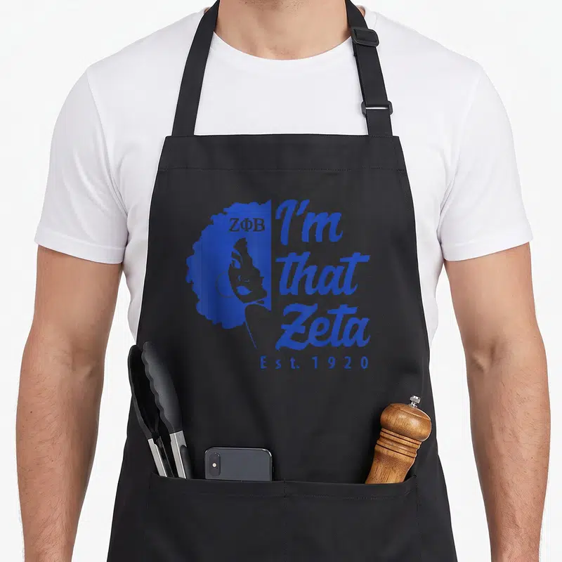 Phi 1920s apron - Blue profile silhouette of woman with curly hair next to I'm that Zeta text and Est 1920 — shown on a black cotton canvas apron against a white background