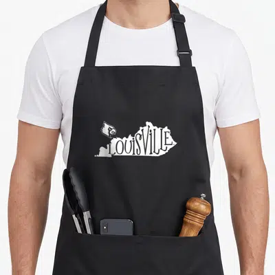 Iconic cardinal apron - White LOUISVILLE text shaped like Kentucky state map with cardinal bird logo on left — shown on a black cotton canvas apron against a white background