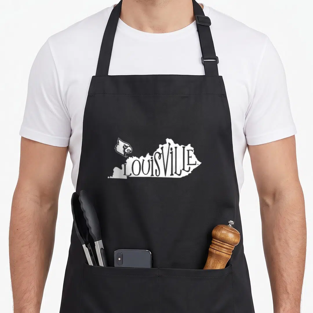 Iconic cardinal apron - White LOUISVILLE text shaped like Kentucky state map with cardinal bird logo on left — shown on a black cotton canvas apron against a white background