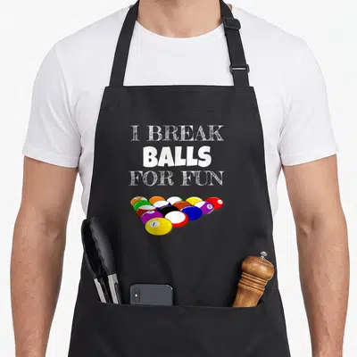 Player sarcasm billiards apron - I break balls for fun text above cartoon billiard balls in white yellow red blue green — shown on a black cotton canvas apron against a white background