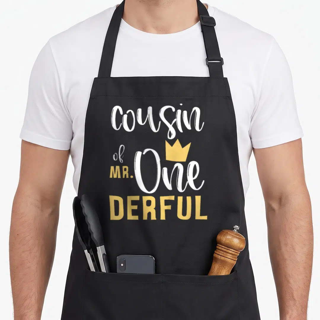 Cousin onederful birthday apron - White and yellow typography reading cousin of MR One DERFUL with a yellow crown — shown on a black cotton canvas apron against a white background