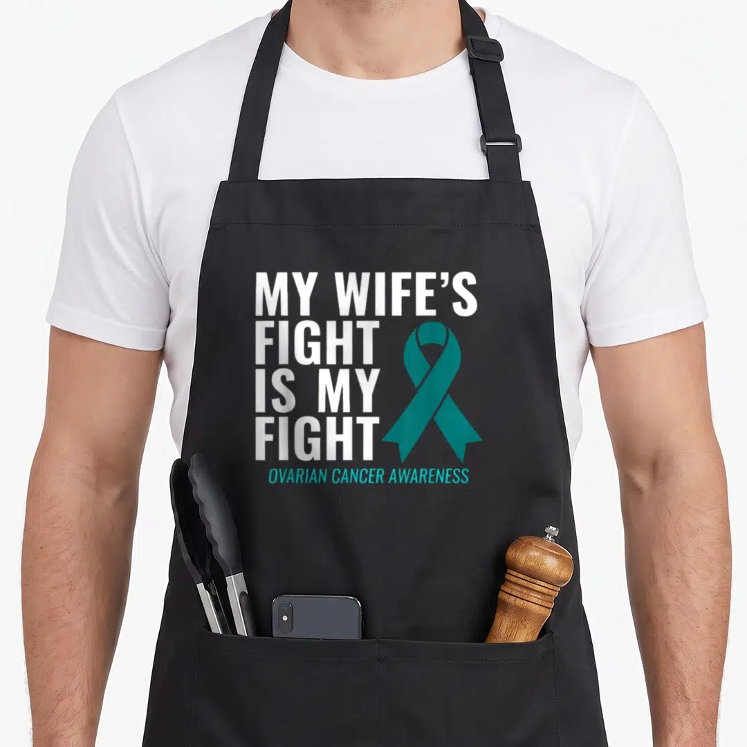 Fight ovarian wife apron - Stacked white text and teal ribbon reading My Wife's Fight Is My Fight Ovarian Cancer — shown on a black cotton canvas apron against a white background
