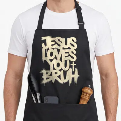 Bruh funny christian aprons - Stacked beige text reading JESUS LOVES YOU BRUH with a small cross next to YOU — shown on a black cotton canvas apron against a white background