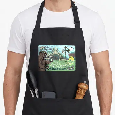 Midsommar bear apron - Brown bear with flower crown holding drink near maypole and GLAD MIDSOMMAR text — shown on a black cotton canvas apron against a white background