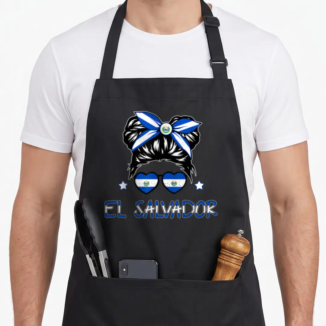 Salvador flag salvadoran apron - Cartoon messy bun with bow, heart sunglasses, stars, and EL SALVADOR text — shown on a black cotton canvas apron against a white background