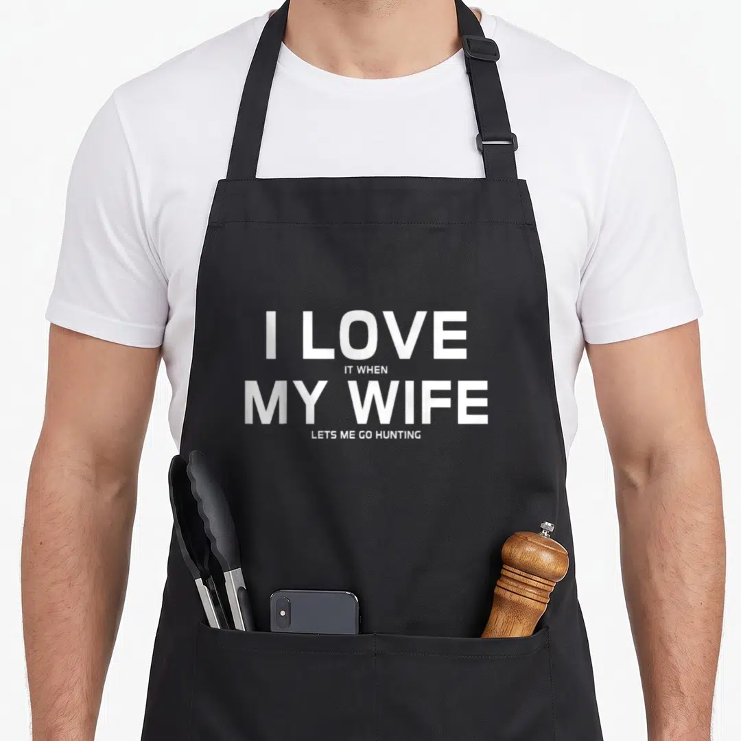 Hunting wife apron - White stacked text reading I LOVE IT WHEN MY WIFE LETS ME GO HUNTING — shown on a black cotton canvas apron against a white background