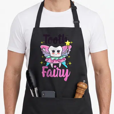 Fairy dentist apron - Cartoon tooth fairy with pink wings holding a star wand, surrounded by yellow sparkles and bold — shown on a black cotton canvas apron against a white background