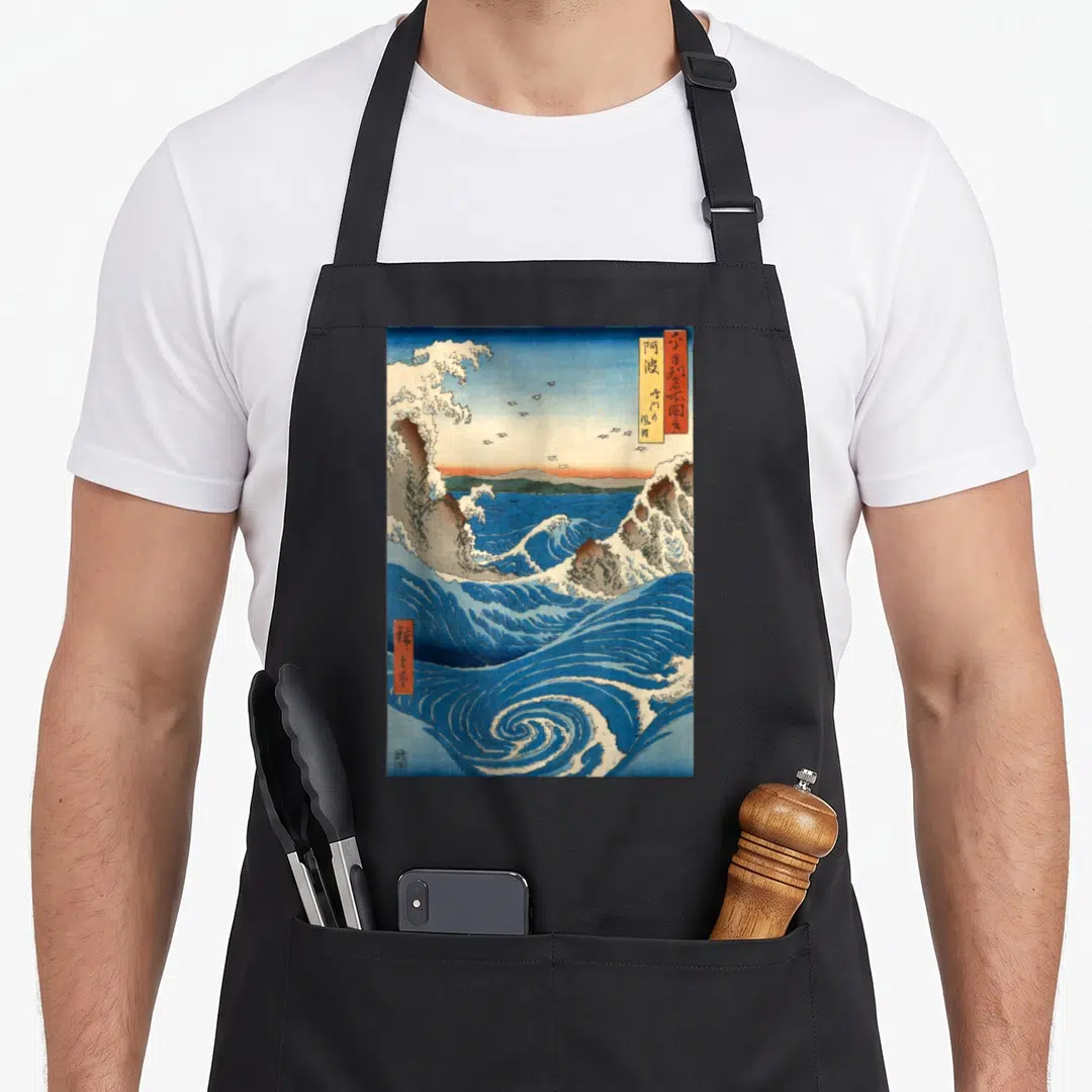 Navaro japanese apron - Blue and white swirling ocean waves with orange sky and kanji text boxes in retro Japanese art — shown on a black cotton canvas apron against a white background