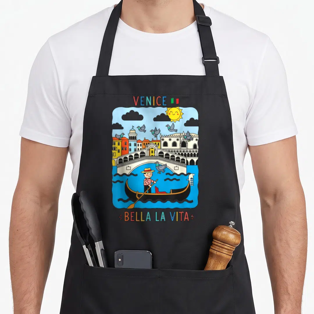 Pigeon italy apron - Cartoon Venice scene with gondola, pigeons, bridge, and Bella La Vita text — shown on a black cotton canvas apron against a white background