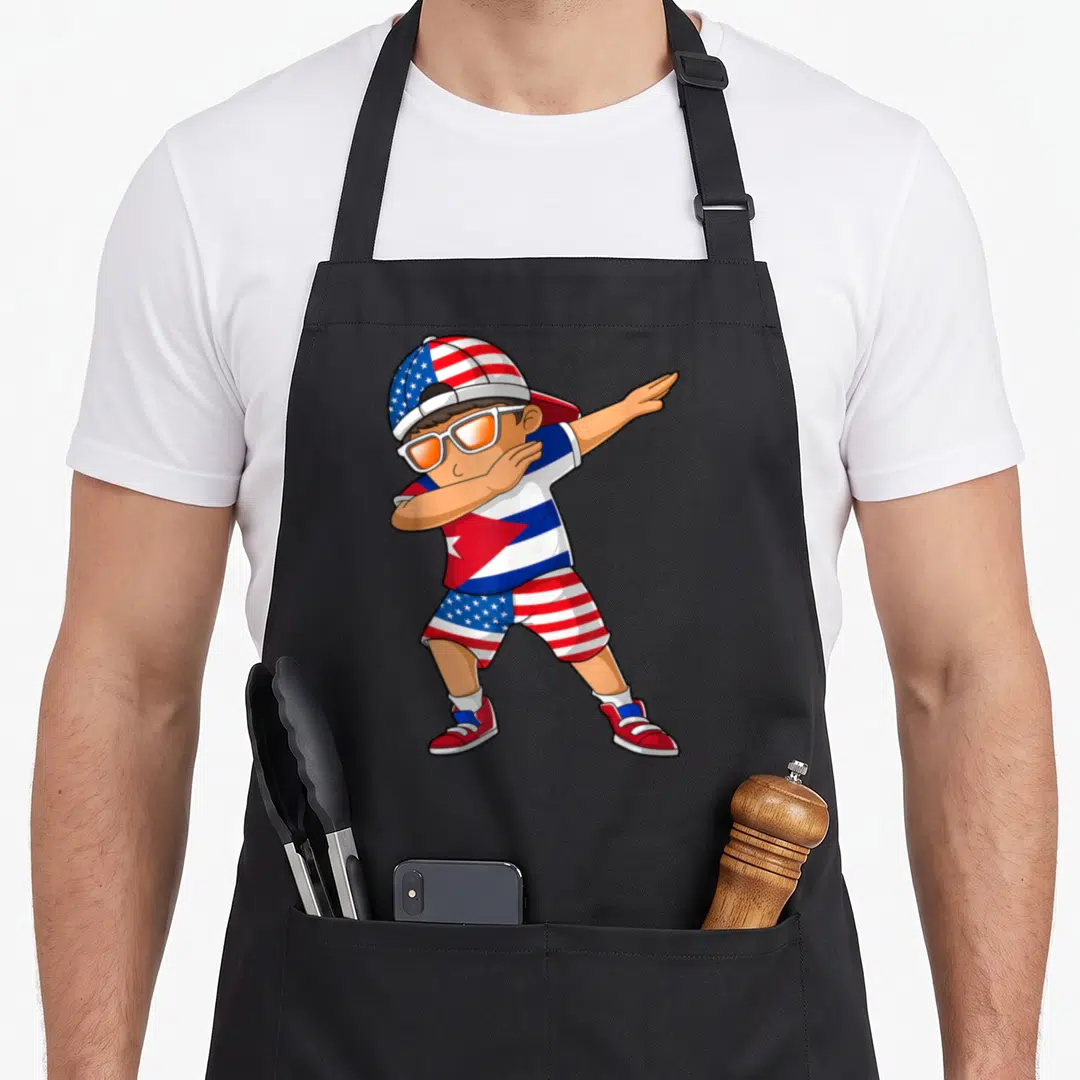 Cuba patriotic american flag apron - Cartoon boy dabbing wearing clothes patterned with American and Cuban flags in red — shown on a black cotton canvas apron against a white background