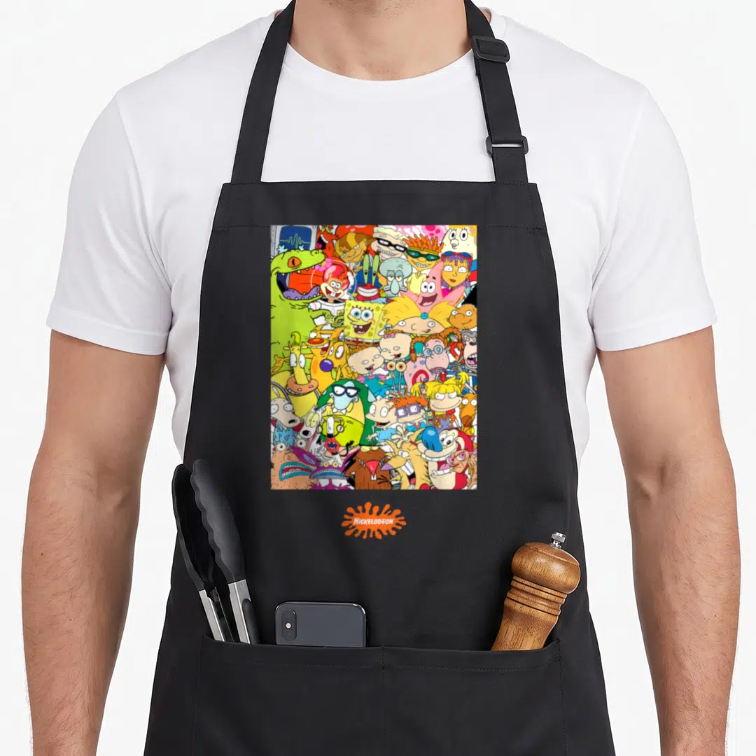 Shot character aprons - Dense cluster of cartoon characters with centered NICKELODEON logo in orange splat — shown on a black cotton canvas apron against a white background