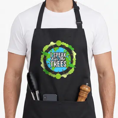 Speak tree apron - I SPEAK For The TREES text over blue green Earth surrounded by trees — shown on a black cotton canvas apron against a white background