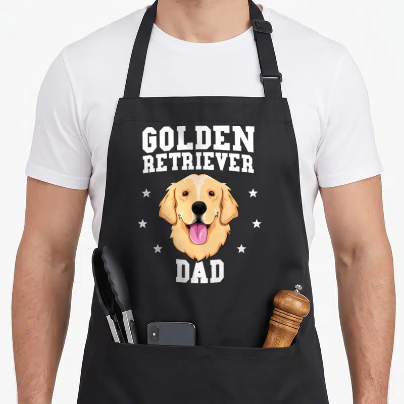 Father dog golden retriever apron - Cartoon golden retriever head with white stars and text GOLDEN RETRIEVER DAD — shown on a black cotton canvas apron against a white background