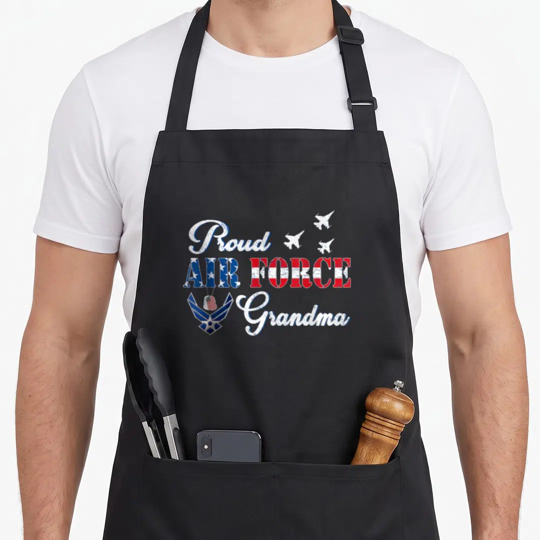 Grandma 4th of july apron - Proud Air Force Grandma text with flag fill, planes, emblem, and dog tag on black background — shown on a black cotton canvas apron against a white background