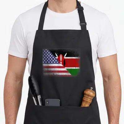 Kenyan kenya american flag apron - Distressed diagonal merge of USA and Kenya flags showing red white blue black green — shown on a black cotton canvas apron against a white background