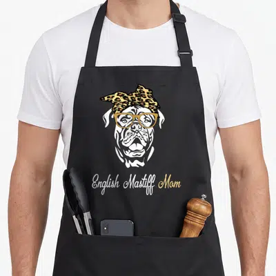 Birthday english aprons - Cartoon mastiff head with glasses and leopard bandana above English Mastiff Mom script text — shown on a black cotton canvas apron against a white background