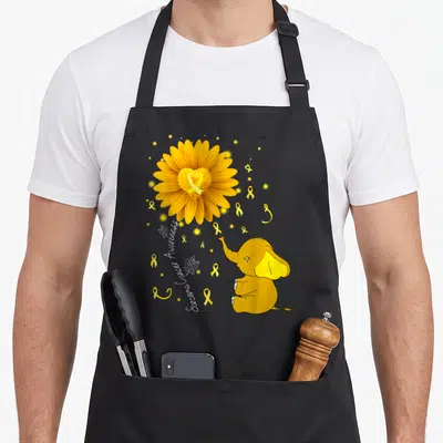 Ribbon daisy apron - Yellow daisy with heart center, cartoon elephant, and Sarcoma Cancer Awareness text on black — shown on a black cotton canvas apron against a white background