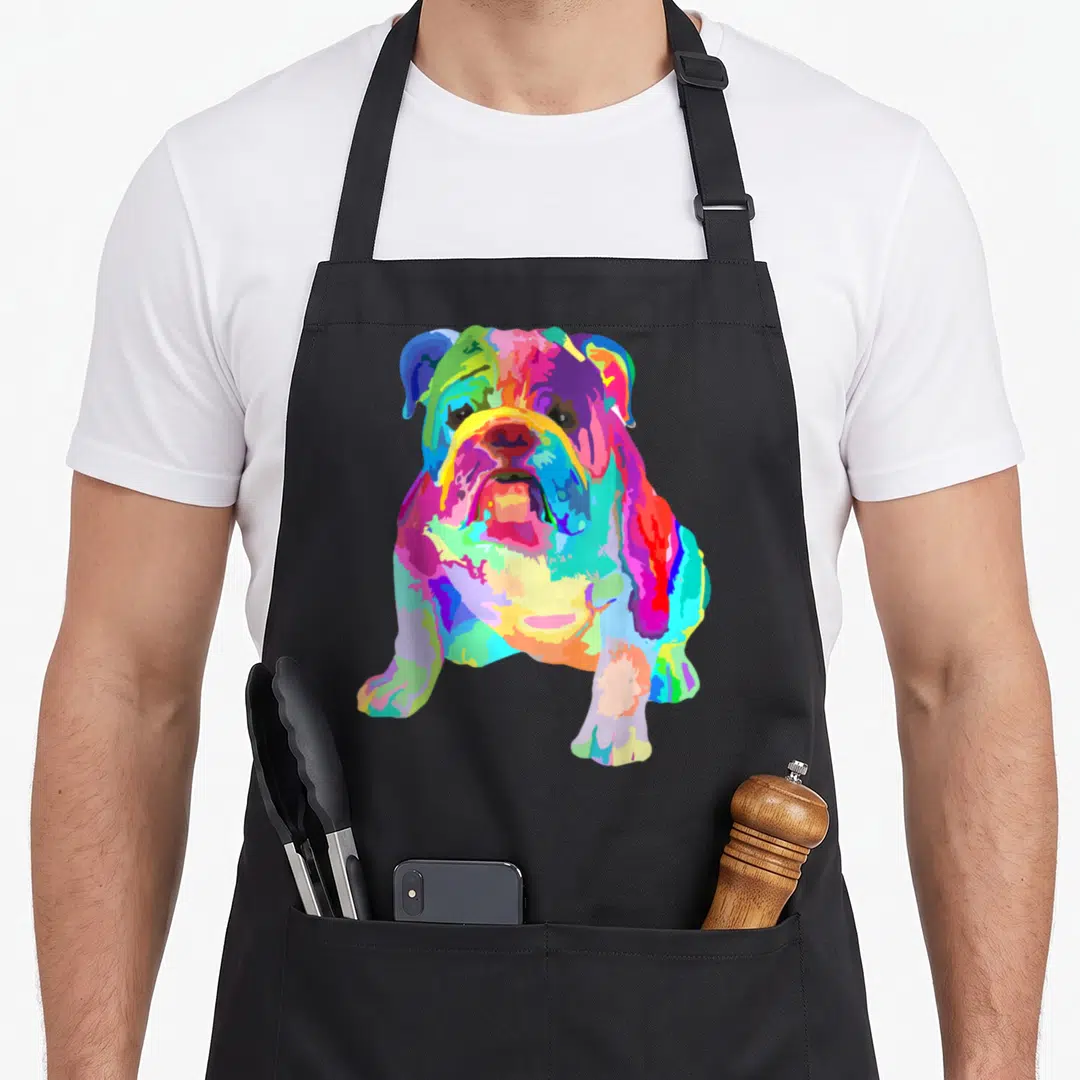 Dog english apron - Multicolored cartoon bulldog illustration in blue, green, yellow, red, and pink segments — shown on a black cotton canvas apron against a white background