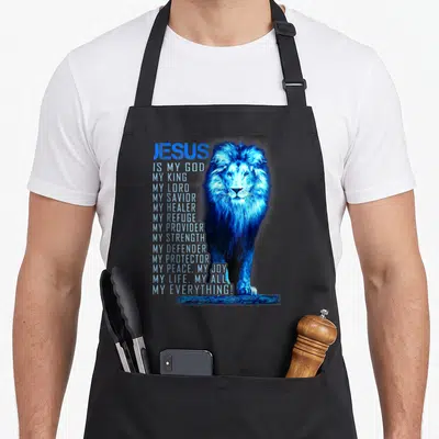 God christian apron - Blue lion standing next to vertical text JESUS IS MY GOD MY KING MY SAVIOR — shown on a black cotton canvas apron against a white background