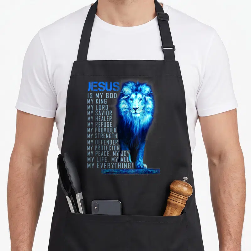 God christian apron - Blue lion standing next to vertical text JESUS IS MY GOD MY KING MY SAVIOR — shown on a black cotton canvas apron against a white background