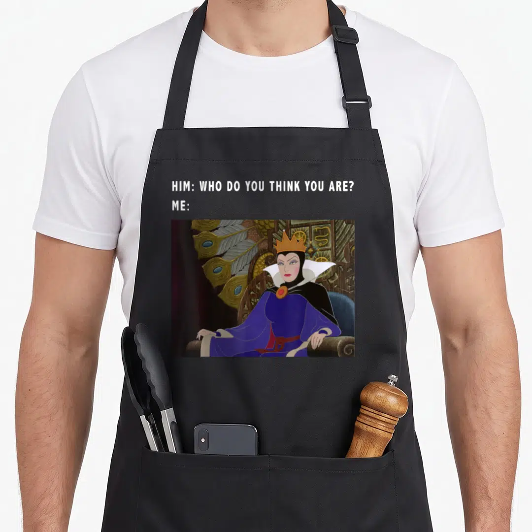 Evil beauty apron - Evil Queen on throne with purple robe and text HIM WHO DO YOU THINK YOU ARE ME — shown on a black cotton canvas apron against a white background