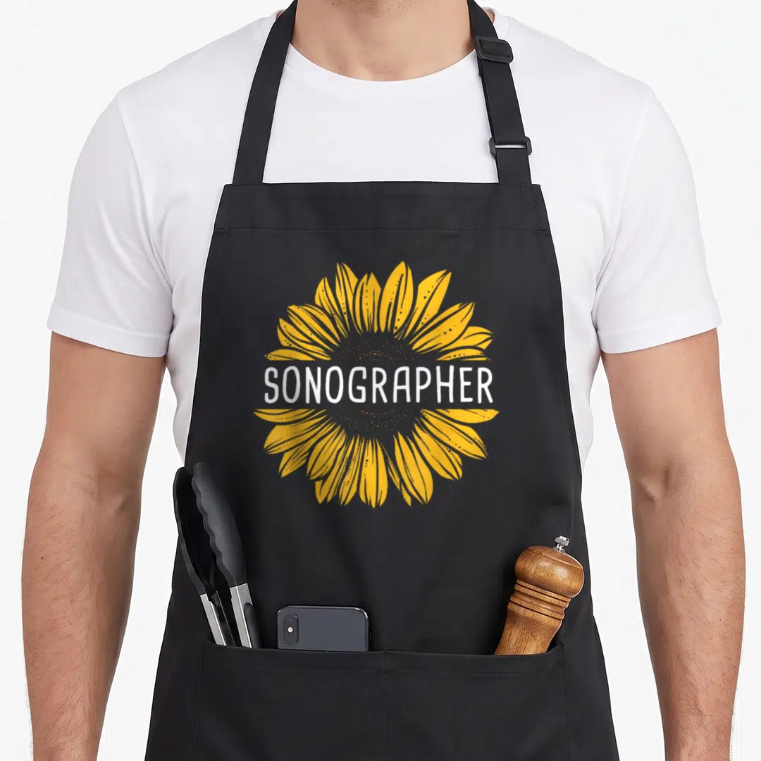 Sonographer sunflower apron - White SONOGRAPHER text over a yellow sunflower graphic — shown on a black cotton canvas apron against a white background