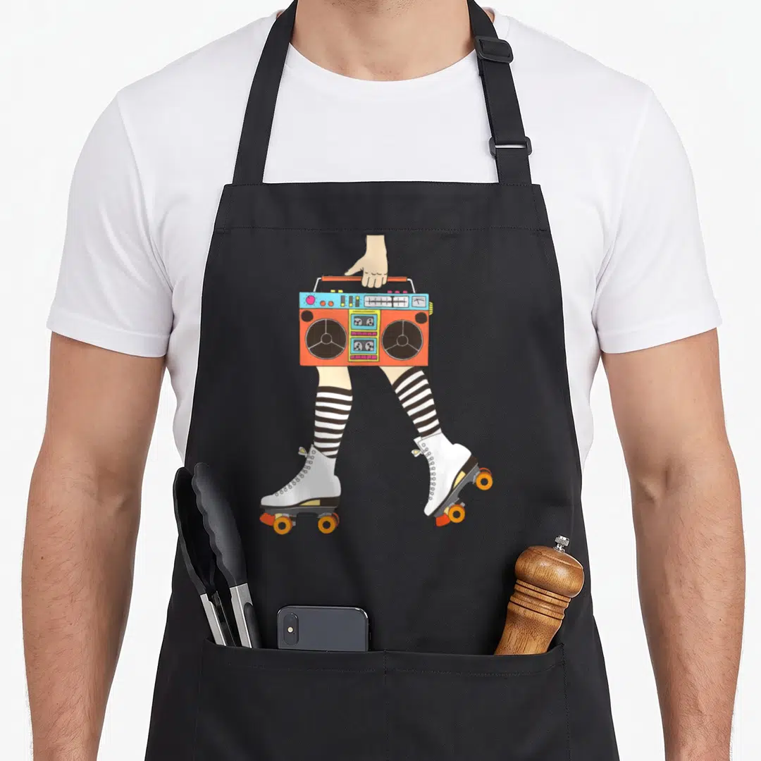 Skating roller derby apron - Cartoon boombox held above legs in striped socks and white roller skates with orange wheels — shown on a black cotton canvas apron against a white background