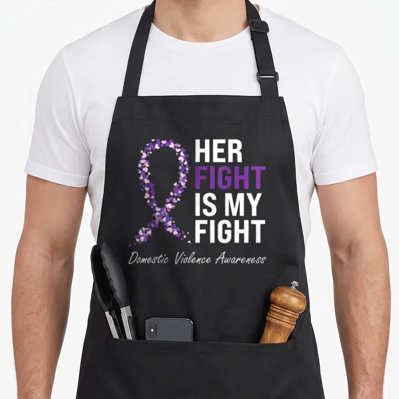 Family violence domestic aprons - Purple and white heart-shaped awareness ribbon with stacked text HER FIGHT IS MY FIGHT — shown on a black cotton canvas apron against a white background