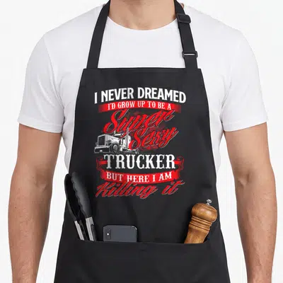 Trucker driver rig semi truck apron - Stacked red and white text with a white truck graphic and ribbon banners — shown on a black cotton canvas apron against a white background