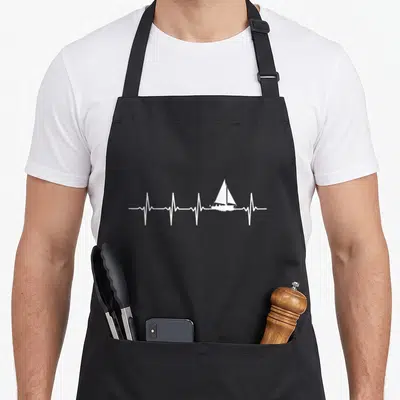 Sailing boat apron - White minimalist sailboat integrated into a horizontal heartbeat line on a dark background — shown on a black cotton canvas apron against a white background