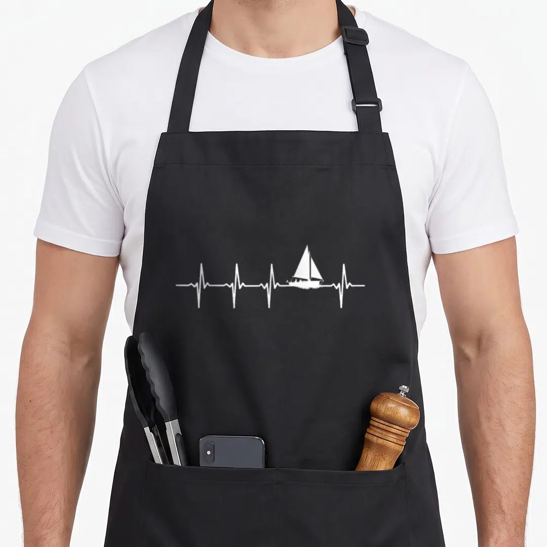 Sailing boat apron - White minimalist sailboat integrated into a horizontal heartbeat line on a dark background — shown on a black cotton canvas apron against a white background