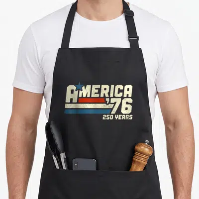 250th novelty apron - Retro AMERICA '76 text with blue star and three red white blue stripes — shown on a black cotton canvas apron against a white background