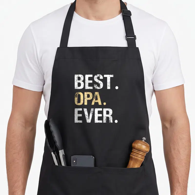 Crew father day apron - Best Opa Ever text in white and gold stacked typography — shown on a black cotton canvas apron against a white background