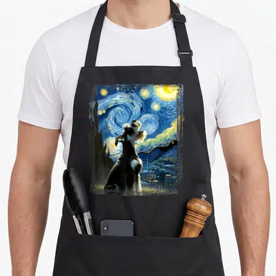 Starry schnauzer apron - Schnauzer dog sitting under swirling blue starry night sky with yellow moon and village — shown on a black cotton canvas apron against a white background