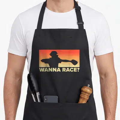 Race baseball apron - Grey catcher silhouette on orange-yellow gradient with WANNA RACE? text below — shown on a black cotton canvas apron against a white background