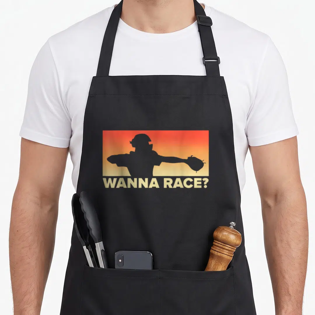 Race baseball apron - Grey catcher silhouette on orange-yellow gradient with WANNA RACE? text below — shown on a black cotton canvas apron against a white background