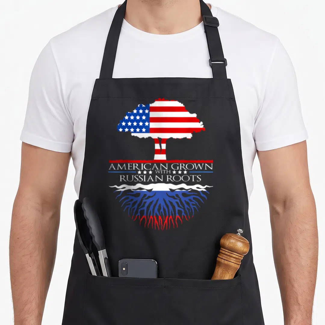 Russia american flag apron - Tree with US flag canopy and Russian flag roots surrounding centered text — shown on a black cotton canvas apron against a white background