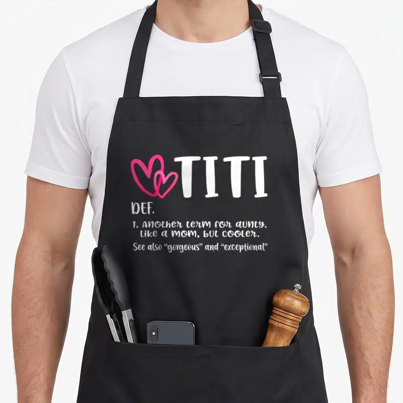 Titi grandma apron - Two pink hearts next to white TITI text with definition lines below — shown on a black cotton canvas apron against a white background
