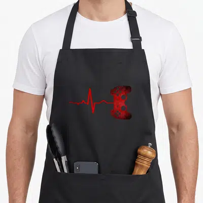 Cute heartbeat video game apron - Red heartbeat line extending from the left and connecting to the left side of a game — shown on a black cotton canvas apron against a white background