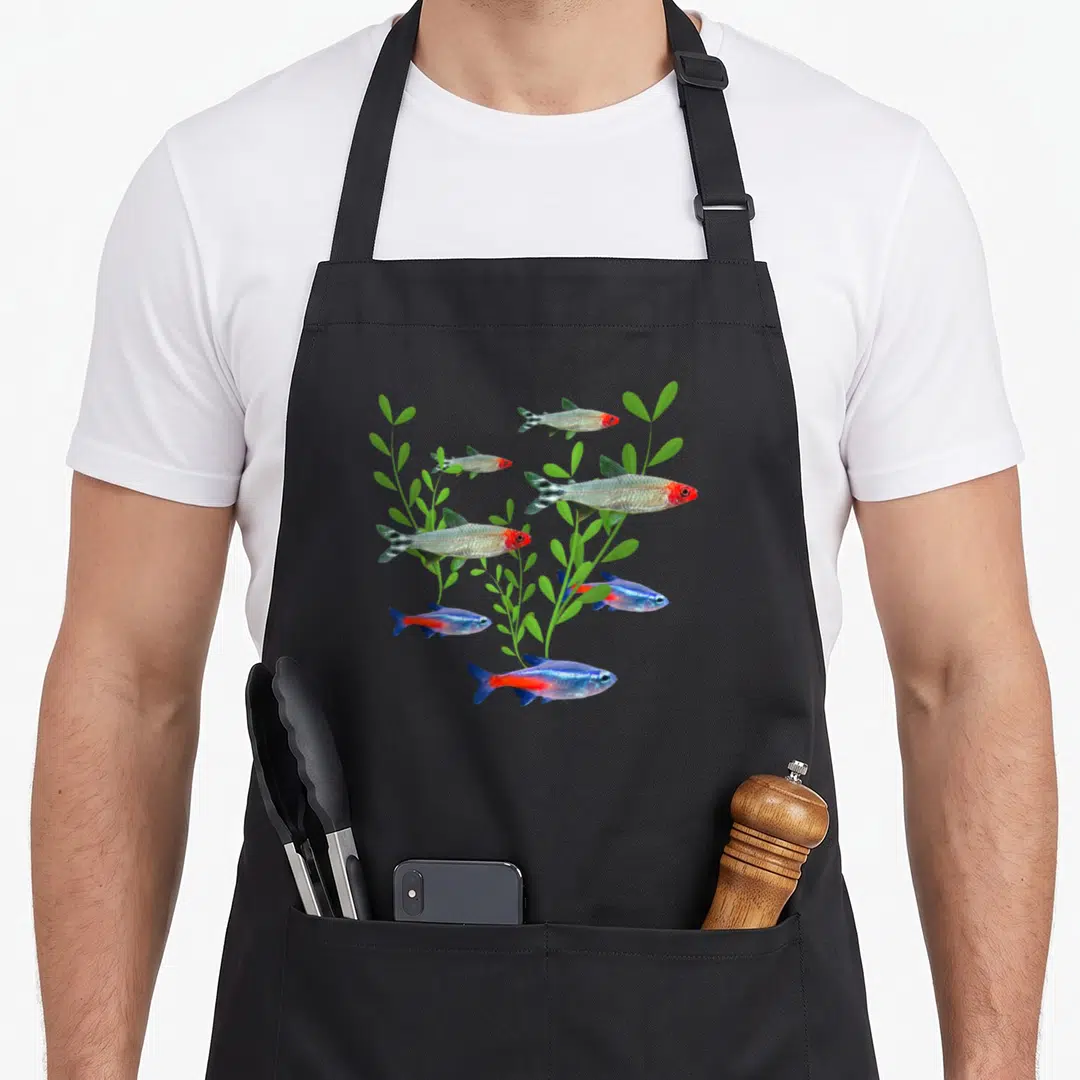Tetras fish apron - Six silver, blue, red, and green fish swimming among green aquatic plants — shown on a black cotton canvas apron against a white background
