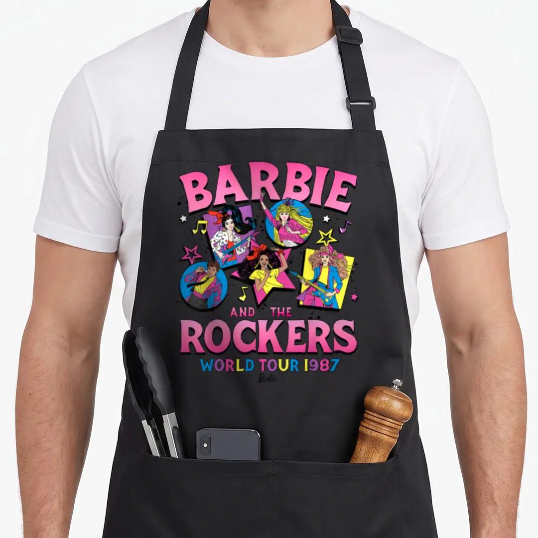 Rocker music apron - BARBIE AND THE ROCKERS WORLD TOUR 1987 text with four cartoon characters in stars and circles — shown on a black cotton canvas apron against a white background