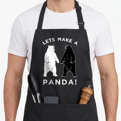 Panda polar bear apron - Two standing bears one white one black with arched text LETS MAKE A PANDA! — shown on a black cotton canvas apron against a white background