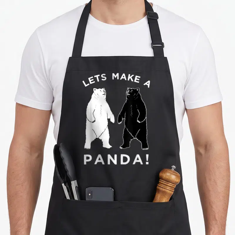Panda polar bear apron - Two standing bears one white one black with arched text LETS MAKE A PANDA! — shown on a black cotton canvas apron against a white background