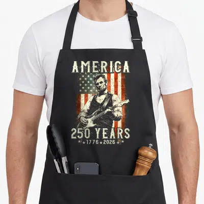 Abraham playing guitar apron - Abraham Lincoln playing electric guitar over distressed red white and blue USA flag — shown on a black cotton canvas apron against a white background