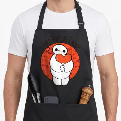 Hero valentine's day apron - Baymax character holding red heart inside circle with arched text WOULD YOU LIKE A HUG — shown on a black cotton canvas apron against a white background